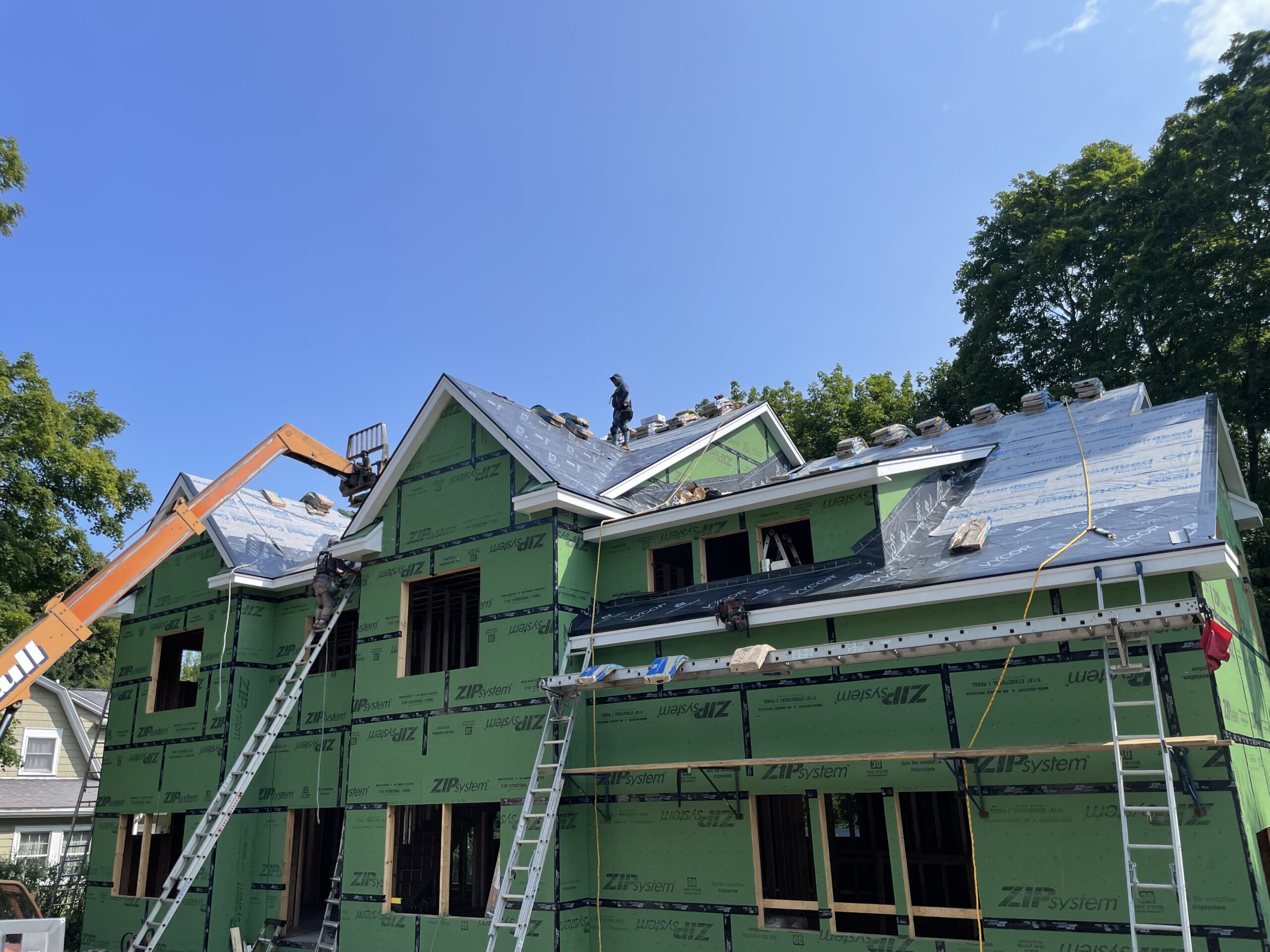 Residential construction project with multiple gables and roofing work in progress